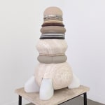 A multi-colored and layered sculpture in neaurals with different mediums and sizes on each layer, the shapes are rounded.