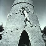Black and White photograph of a man climbing a coned brick structure