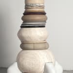 A multi-colored and layered sculpture in neaurals with different mediums and sizes on each layer, the shapes are rounded.