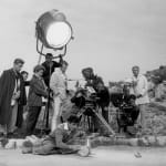 Black and white photograph of Edouard Dermit, Claude Pinoteau and Jean Cocteau filming a scene outside with a large spotlight pointed down over them