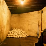 Art installation in World War 2 bunker, with a mound of white plaster egg sculptures in a corner