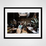 Framed photograph in black wood of two artists, Ken and Flo Jacobs in a loft setting filled with artworks, books, and tools