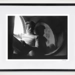 Framed black and white photograph of James Dean sitting by a window holding a book in an apartment setting