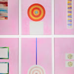 An array of colorful paintings comprised of geometric abstract forms displayed on a white wall