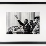 Framed black & white photograph of Martin Luther King Jr. speaking, right hand raised, people behind him visible