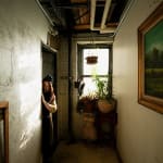 an artist and milliner, Christine Ellen, playfully peeks around a doorway of her loft space