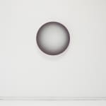 The image features a minimalist artwork of a shaded sphere centered on a white wall. The sphere exhibits a gradient of tones from a light center to darker edges, creating an illusion of depth and three-dimensionality. The play of light and shadow on the s