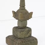 The image shows a traditional stone pagoda sculpture often found in East Asian gardens. The pagoda is constructed with multiple layers, each with its own distinct shape and texture, contributing to the overall tiered design. From the bottom, there's a bro