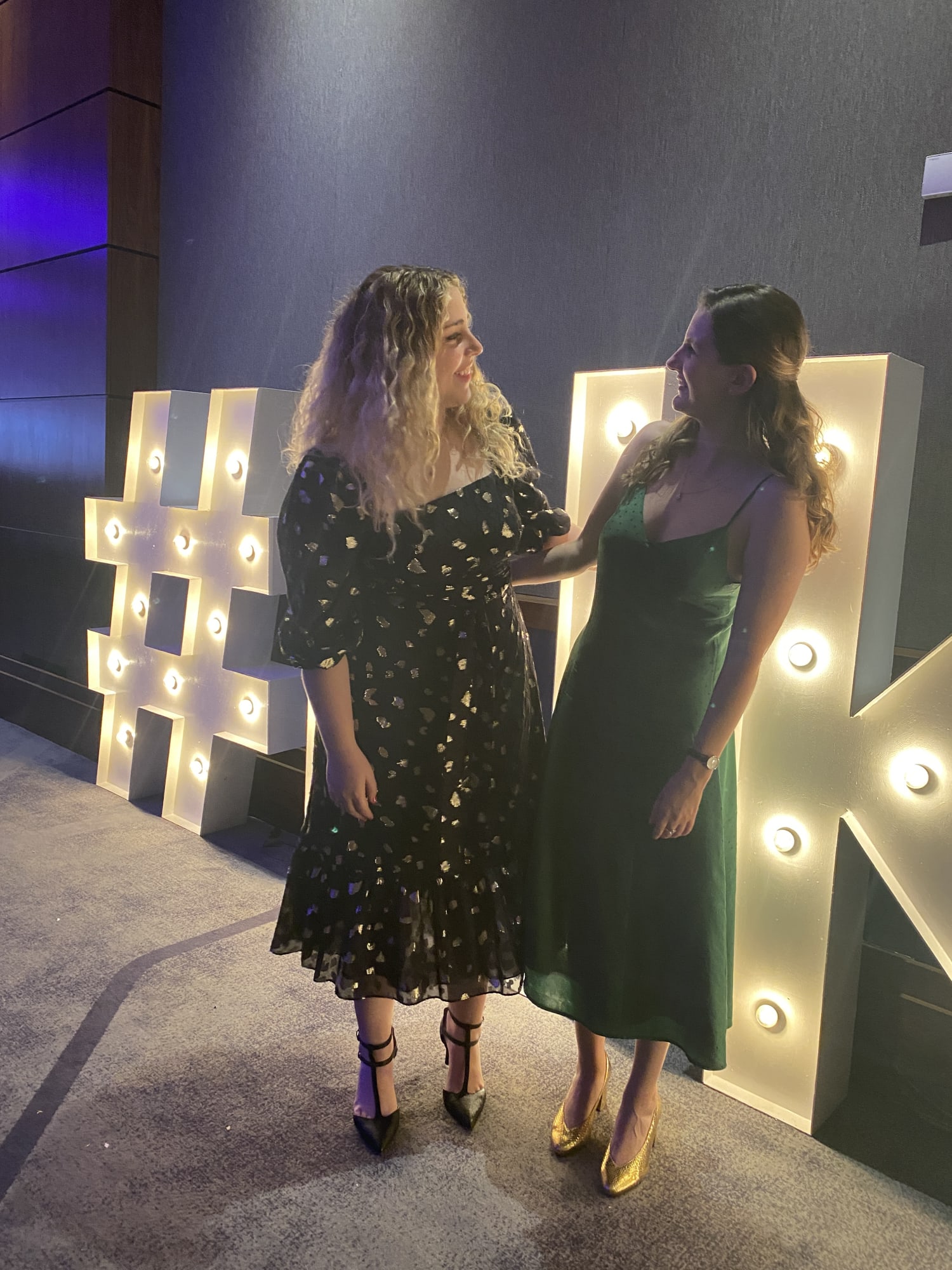 Kayla Rimmon & Chloë Woodmansterne in front of UKJA sign.