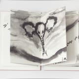 An accordion notebook, opened to a black-and-white painting of an elephant-like skull in the sky.