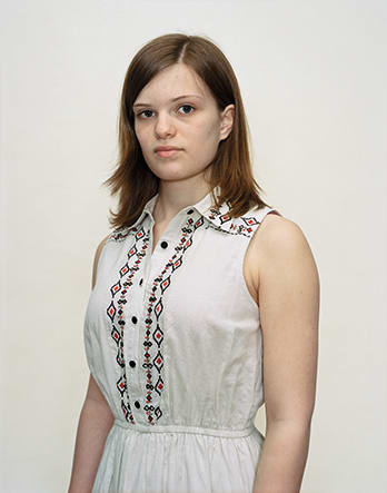 A Rineke Dijkstra portrait of a teenage girl in a white blouse.