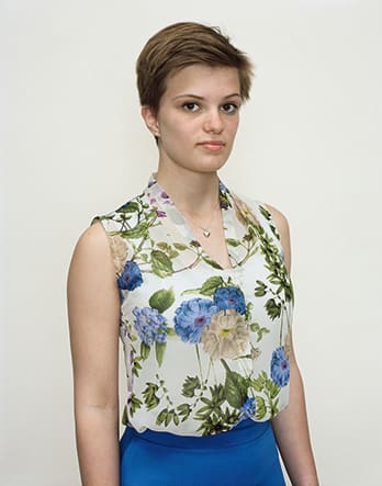 A Rineke Dijkstra portrait of a woman in a floral blouse with short hair.