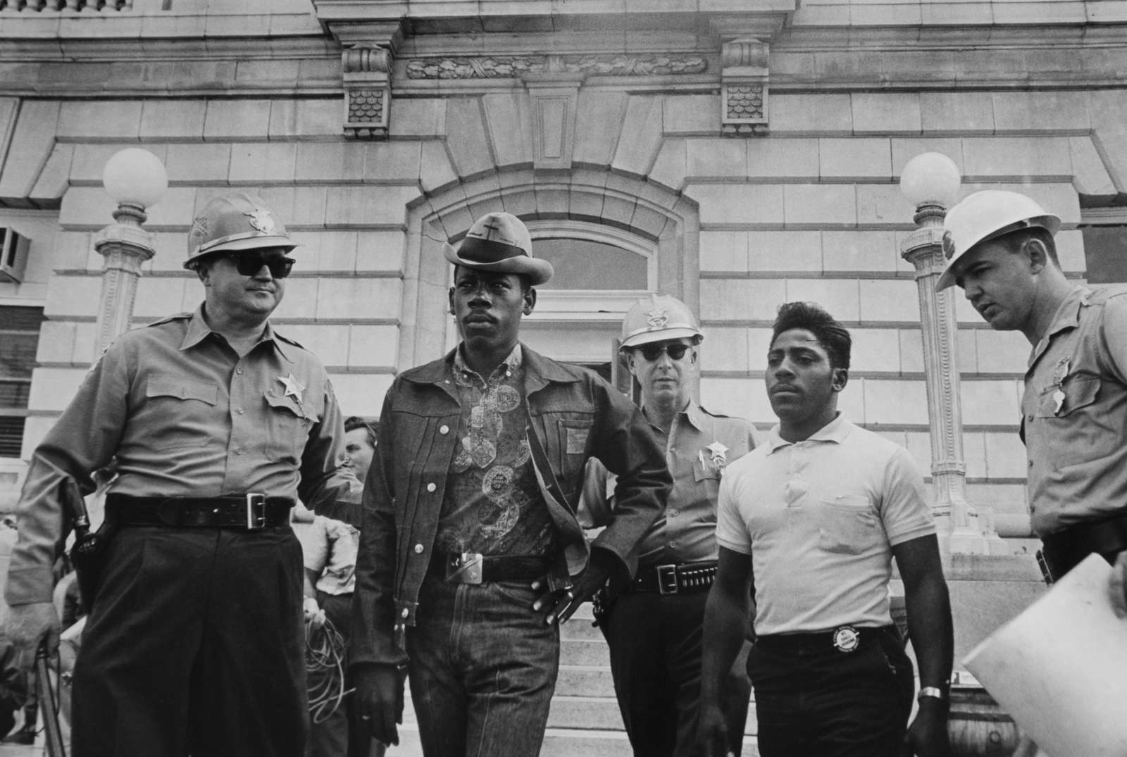 Danny Lyon, Sheriff Jim Clark arrests two demonstrators who displayed placards on the steps of the federal building in Selma, 1963