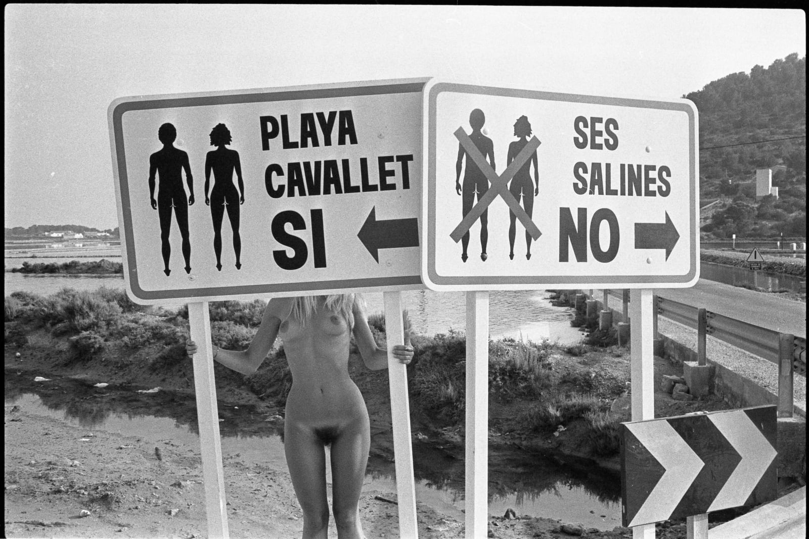 Oriol Maspons, Eva Lyberten behind beach signs, Ses Salines, Ibiza, Spain, cerca 1980