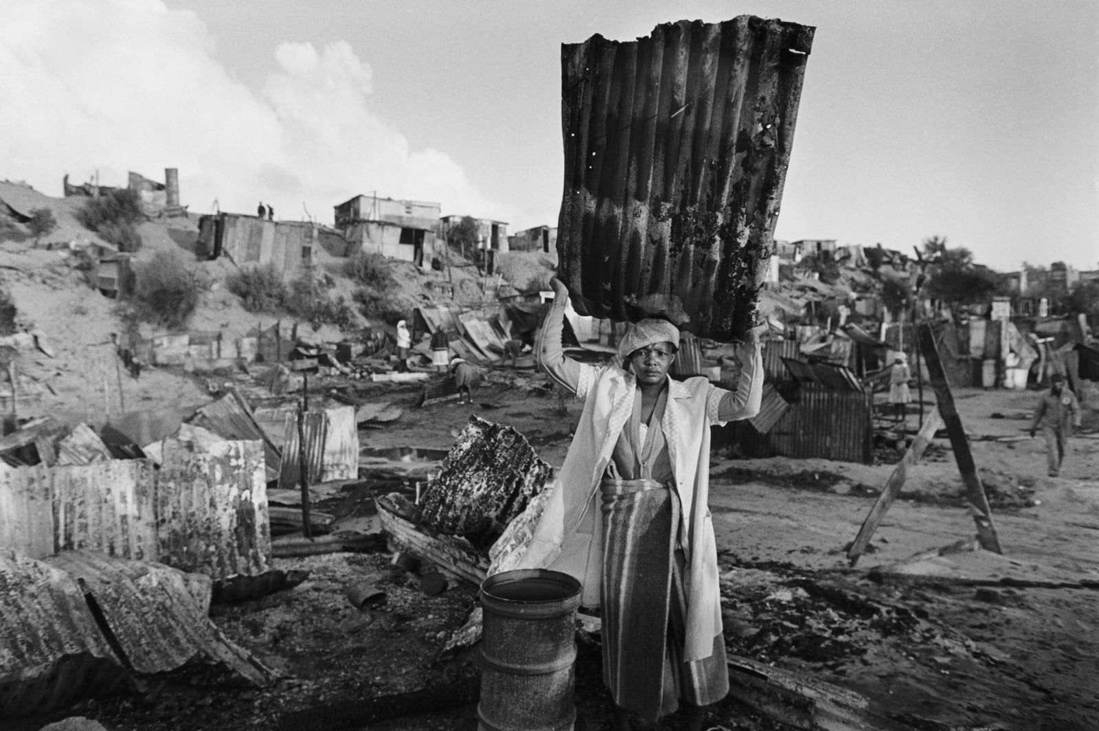 Gideon Mendel, A WOMAN SALVAGES BUILDING MATERIAL AFTER HER SHACK WAS BURNT... , 1986
