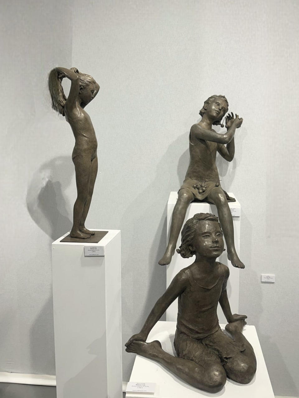 bronze sculpture, The Little Bather, Béatrice Cols, Belgian artist, bronze child sculpture, girl in swimsuit, figurative art, tying ponytail, natural patina, poetic sculpture, contemporary bronze, interior decor, garden sculpture, patinated bronze, art collector piece
