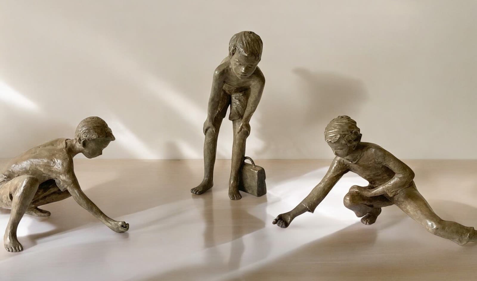 Les joueurs de billes, petite sculpture figurative en bronze par Béatrice Cols, trois enfants en train de jouer, œuvre poétique de collection pour intérieur