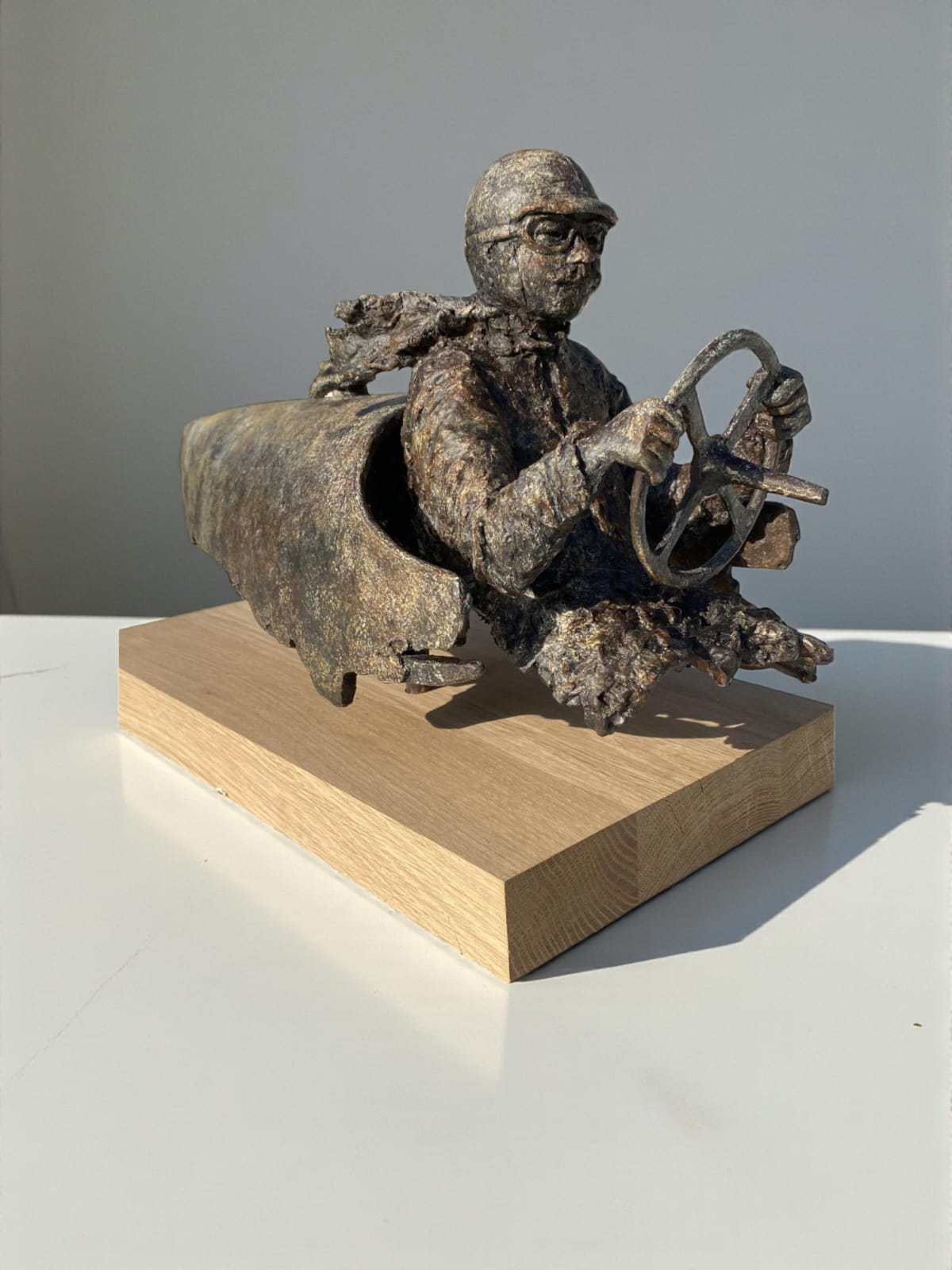 “Master of Speed V” bronze sculpture by Lieven D’Haese, showing a figure seated in a stylised vehicle with a small bird perched on the front.