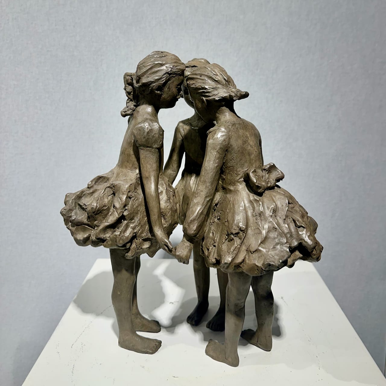 scultura in bronzo, Le Tre Grazie, Béatrice Cols, artista belga, bambini in bronzo, scultura figurativa, bambine in cerchio, abiti svolazzanti, arte contemporanea, scultura poetica, decorazione interni, scultura da giardino, bronzo patinato, opera da collezione, scultura decorativa