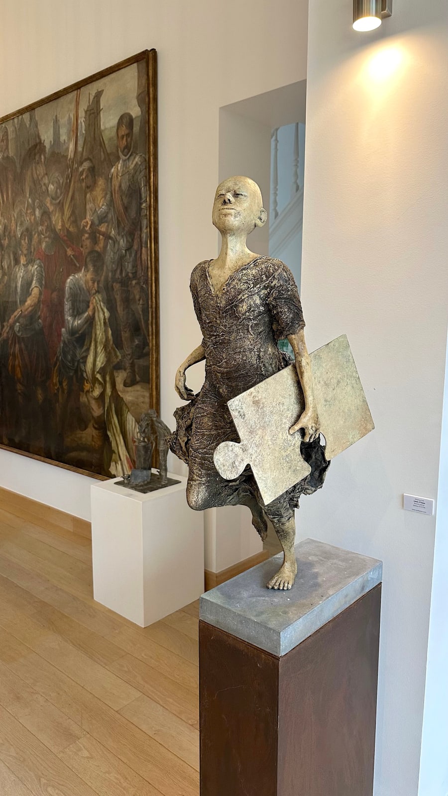 Missing Link, monumentale hedendaagse sculptuur van Lieven D’Haese met een rennende figuur die een puzzelstuk vasthoudt, symbolisch kunstwerk voor verzamelaars en interieur- of tuinarchitecten.