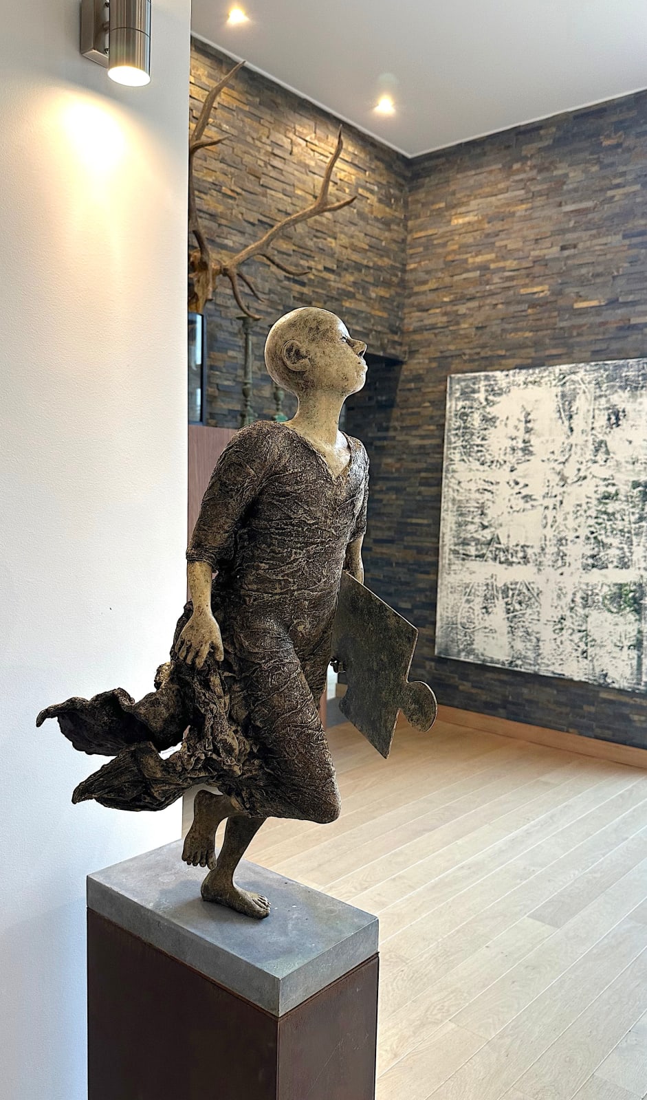 Missing Link, scultura monumentale contemporanea di Lieven D’Haese raffigurante un uomo in corsa con un pezzo di puzzle, opera simbolica per collezionisti e architetti d’interni o del paesaggio.