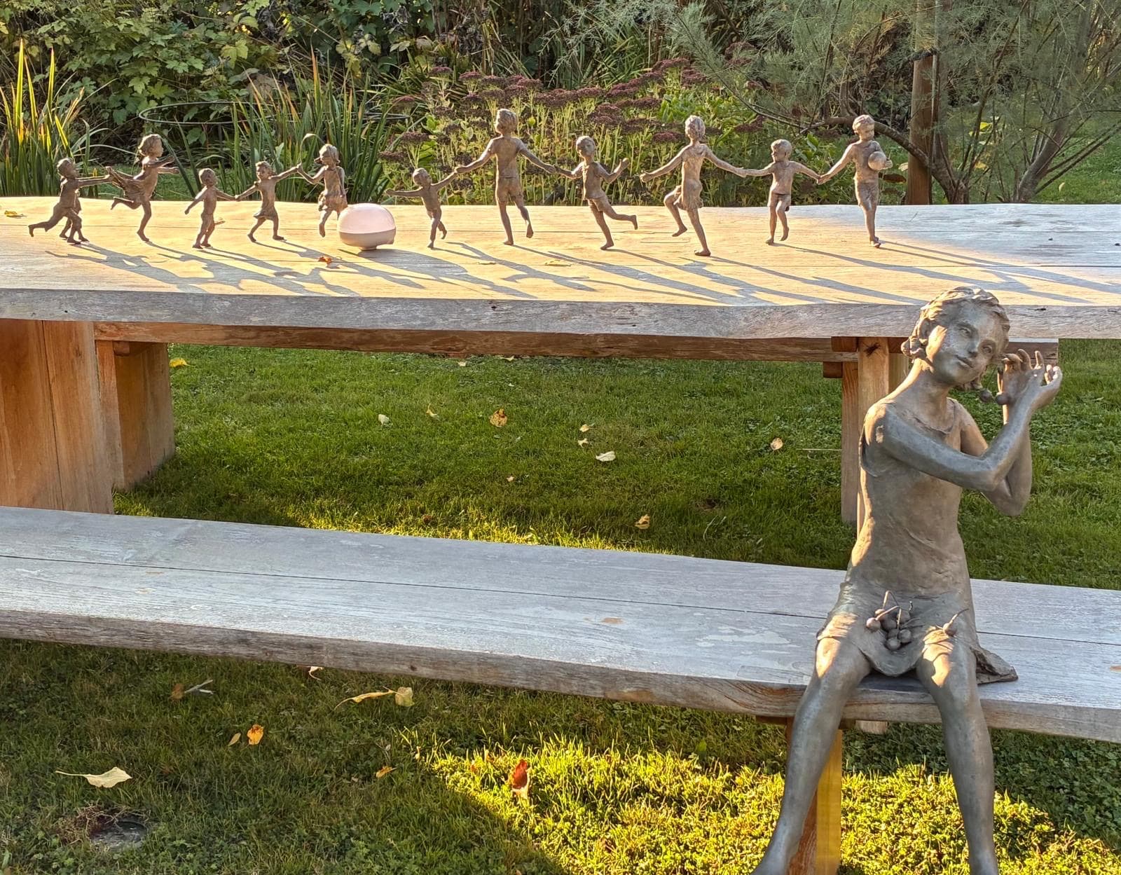 scultura in bronzo, Le Temps des Cerises, Béatrice Cols, artista belga, bambino in bronzo, scultura figurativa, arte contemporanea, scultura di bambina, patina naturale, decorazione da giardino, scultura da collezione, scultura da esterno, scultura per interior designer, bronzo patinato, scultura poetica, galleria d’arte, scultura belga in bronzo, scultura infantile