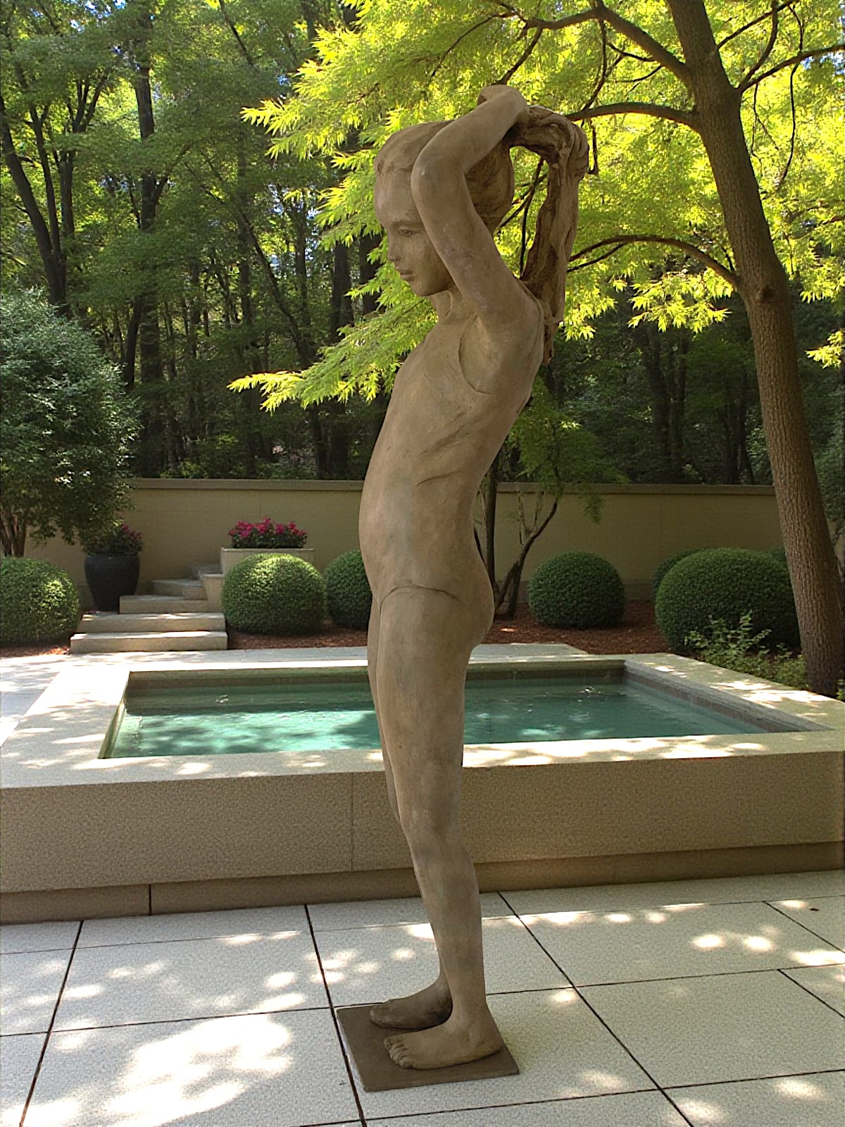 bronzen beeld, Het Kleine Badmeisje, Béatrice Cols, Belgische kunstenares, kind in brons, meisje in badpak, figuratieve sculptuur, paardenstaart maken, natuurlijke patina, poëtisch beeld, hedendaagse kunst, interieurdecoratie, tuinbeeld, gepatineerd brons, kunstcollectie