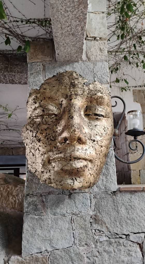 Contemporary wall-mounted mask sculpture in alloy with gold leaf and black patina, a striking sculptural artwork for interior architecture.