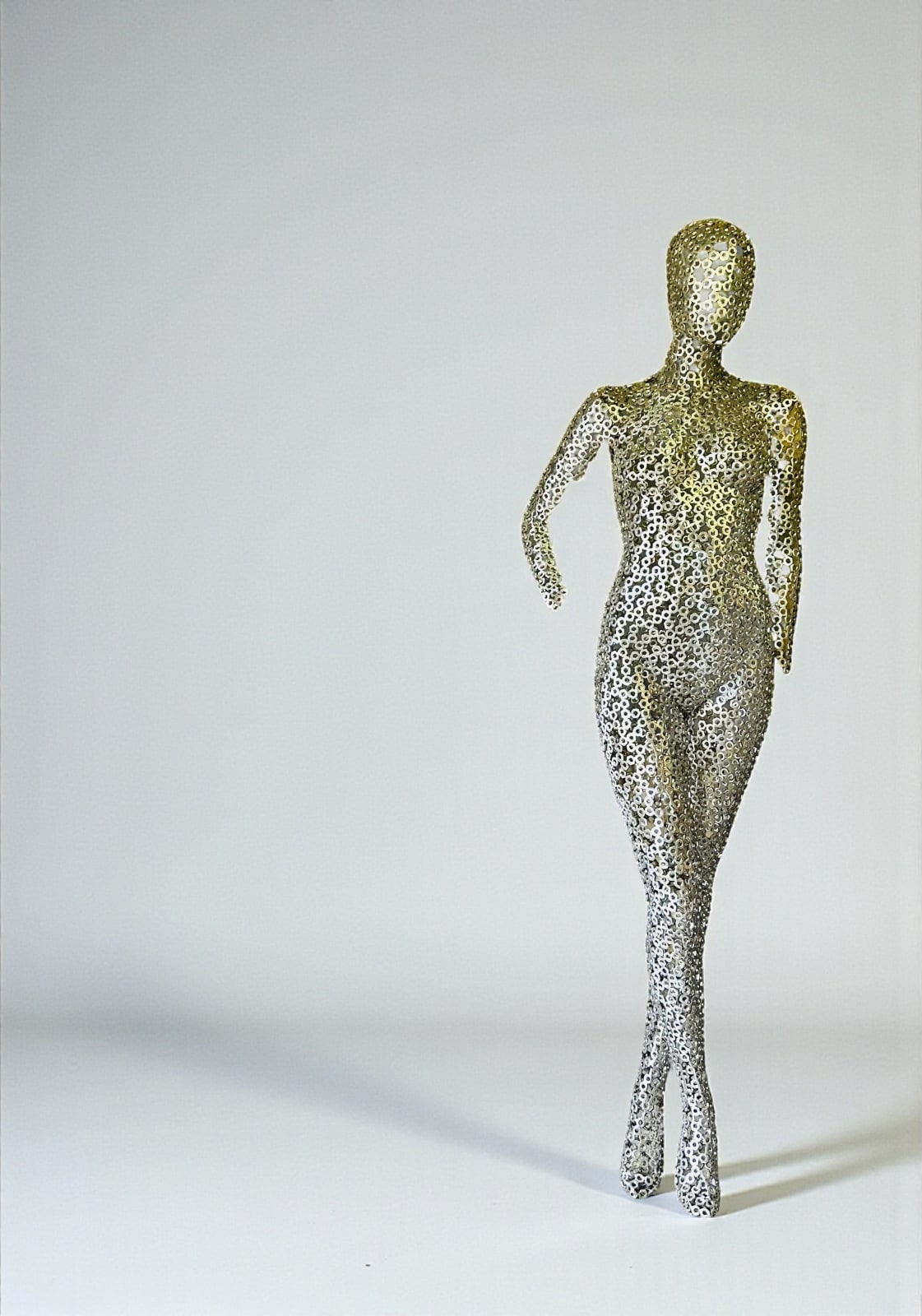 Maia, contemporary brushed stainless steel sculpture by Gregory Castiglia displayed in a garden, a graphic see-through artwork suitable for outdoor and architectural spaces.