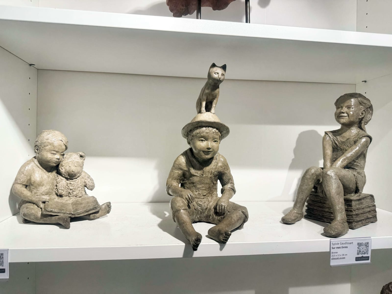 Sur mes livres sculpture bronze Sylvie Gaudissart jolie sculpture fille et garçon lisant des livres à son ours en peluche Galerie Art Yi Galerie d'art de Bruxelles