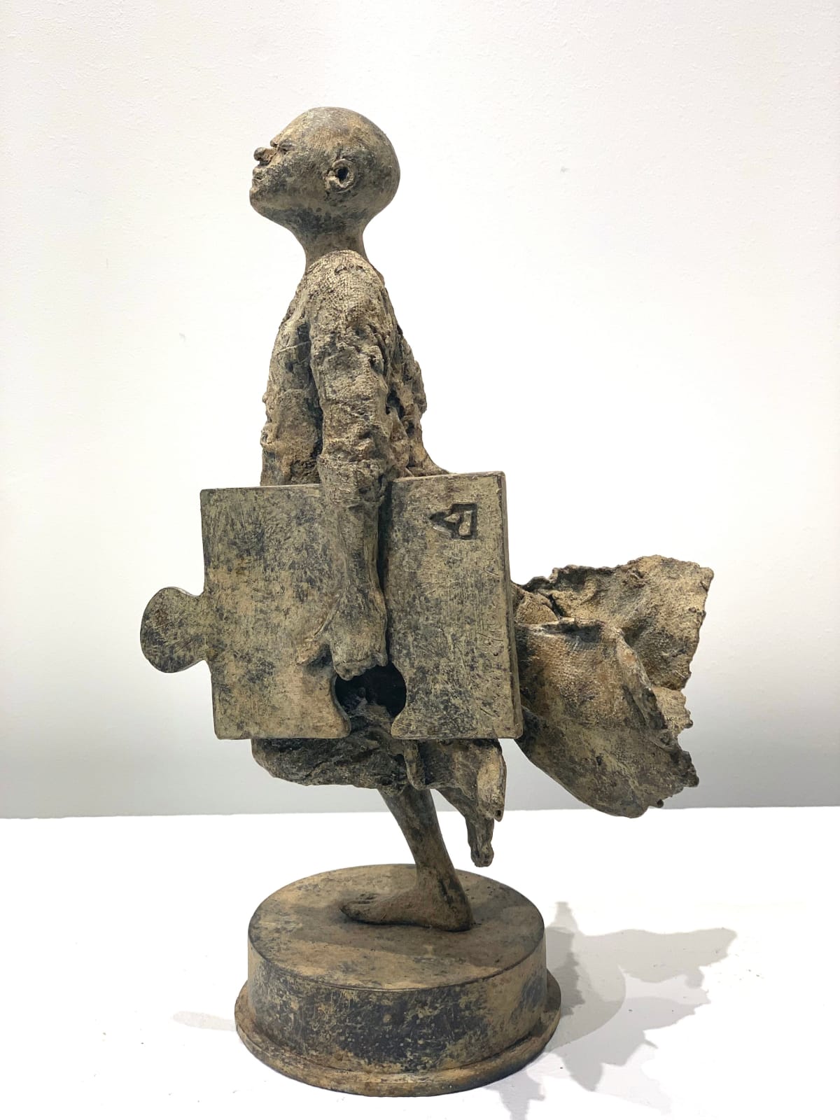 Ontbrekende schakel lieven d'haese hedendaagse bronzen sculptuur een jongen die rent met een puzzel sculptuur kindersculptuur kindertijd Art Yi kunstgalerie in brussel