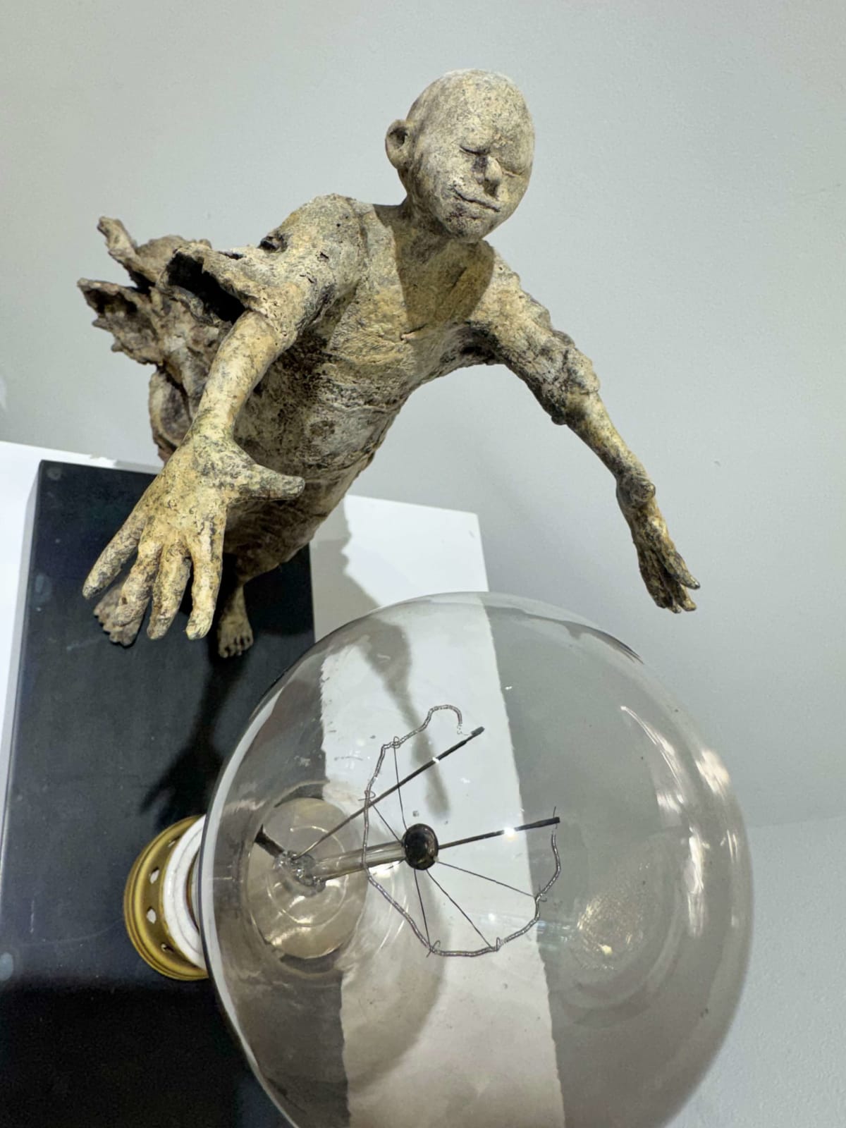 Visionary XL, sculpture lumineuse en bronze de Lieven d'Haese représentant un garçon ouvrant les bras pour allumer une ampoule, symbole d'imagination, de magie et de rêve. Sculpture d'art contemporain, design lumineux et design d'intérieur, exposée à la galerie Art Yi à Bruxelles.