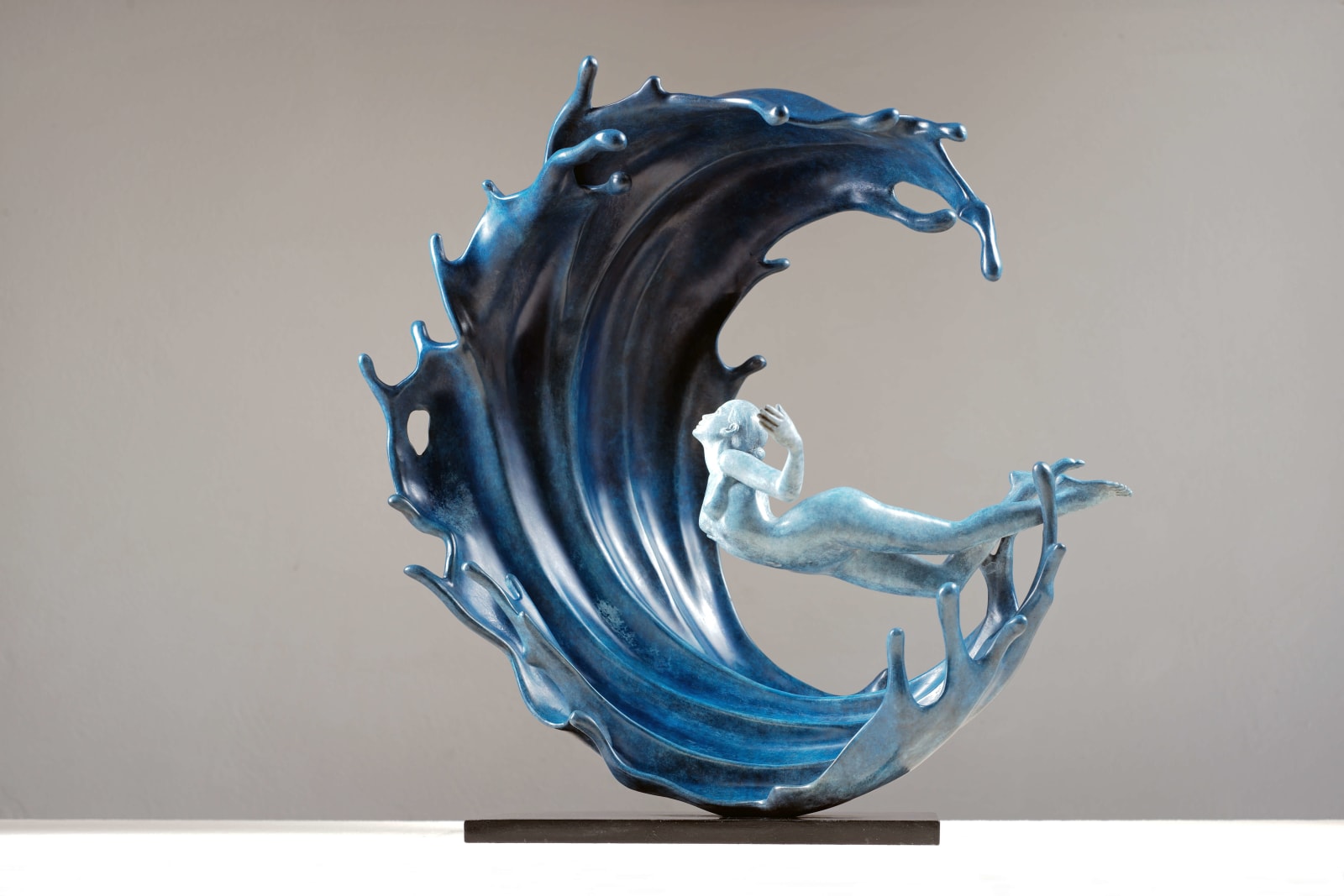 Hedendaagse bronzen sculptuur van machtige golven, Liang Binbin, Chinese kunstenaar, sculptuur van blauw zeewater, een mooi meisje dat zwemt of surft in een grote golf, sculptuurkunst in de Art Yi-galerij in Brussel