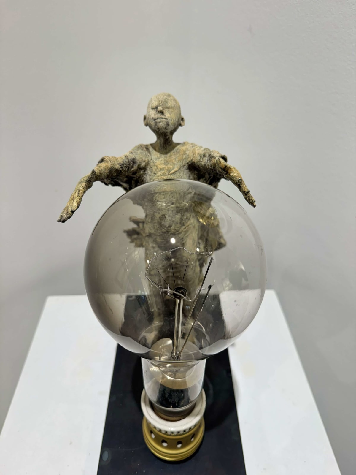 Visionary XL with light boy sculpture bronze sculpture of Lieven d'Haese garden sculpture boy opening arms to light up a light bulb in his hands with imagination magic dream contemporary art sculpture light interior design at Art Yi gallery in Brussels