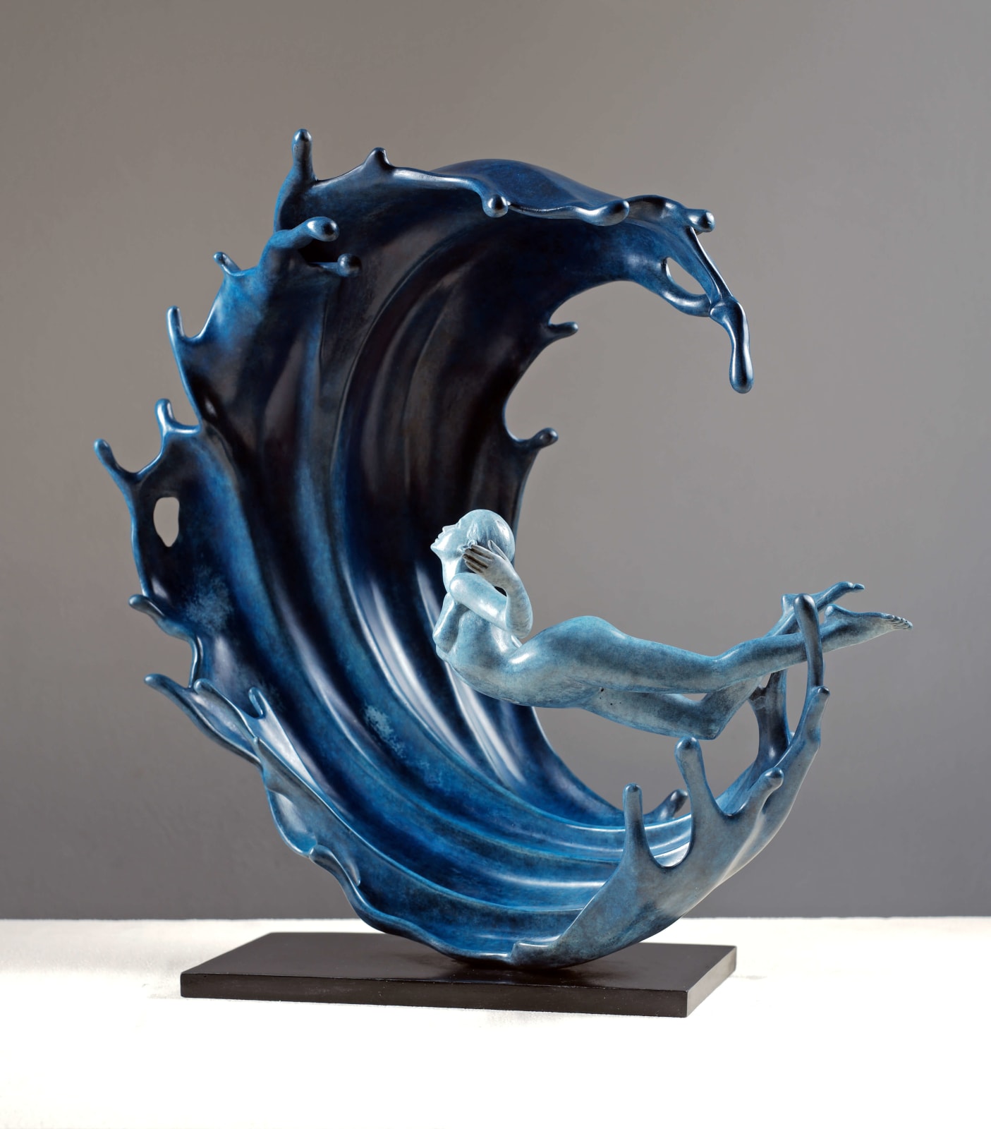 « Vagues puissantes », sculpture contemporaine en bronze de l'artiste chinois Liang Binbin, représentant une jeune fille nageant ou surfant dans une vague immense. Exposition à la galerie Art Yi à Bruxelles.