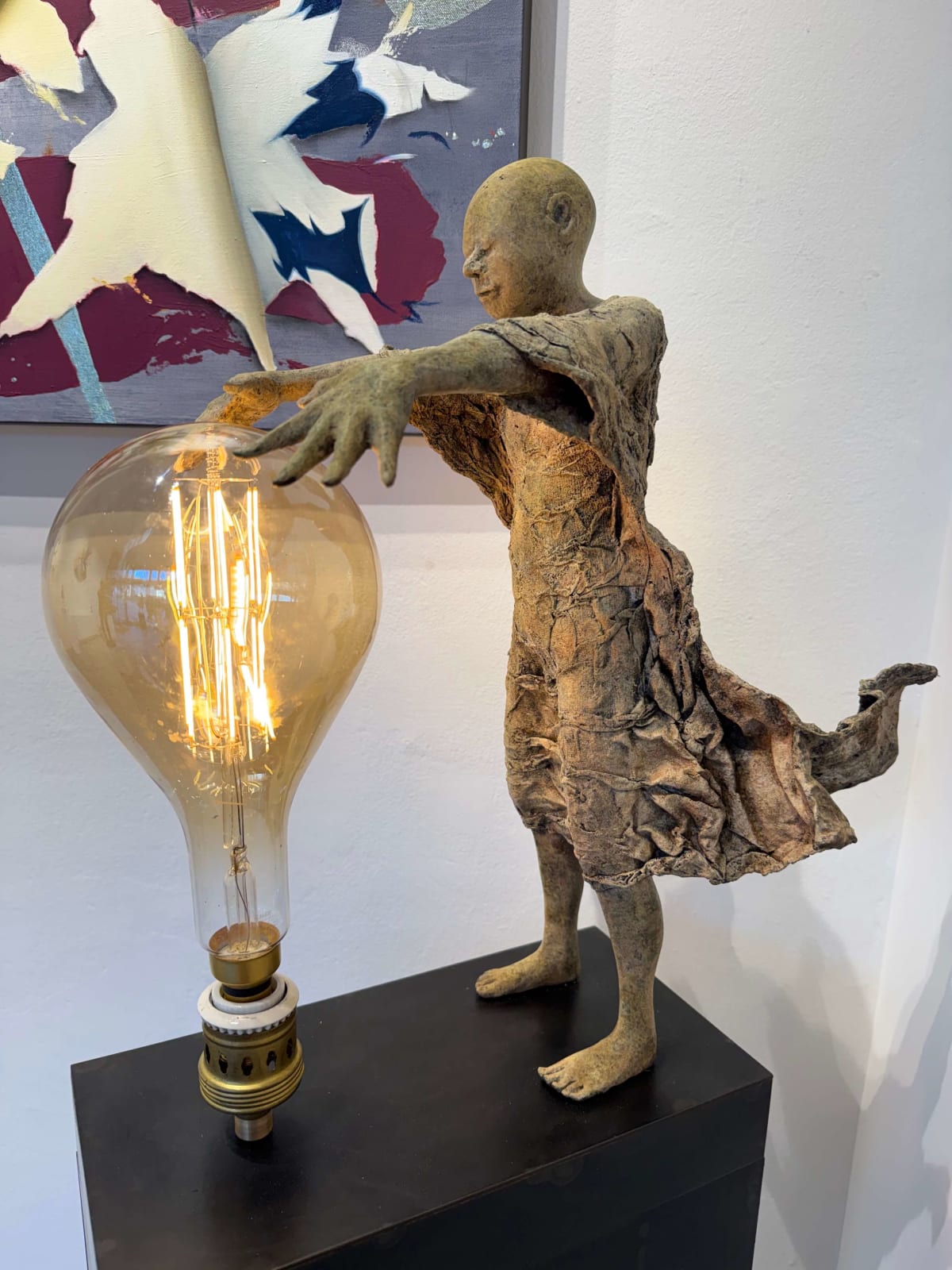 Visionary XL, sculpture lumineuse en bronze de Lieven d'Haese représentant un garçon ouvrant les bras pour allumer une ampoule, symbole d'imagination, de magie et de rêve. Sculpture d'art contemporain, design lumineux et design d'intérieur, exposée à la galerie Art Yi à Bruxelles.