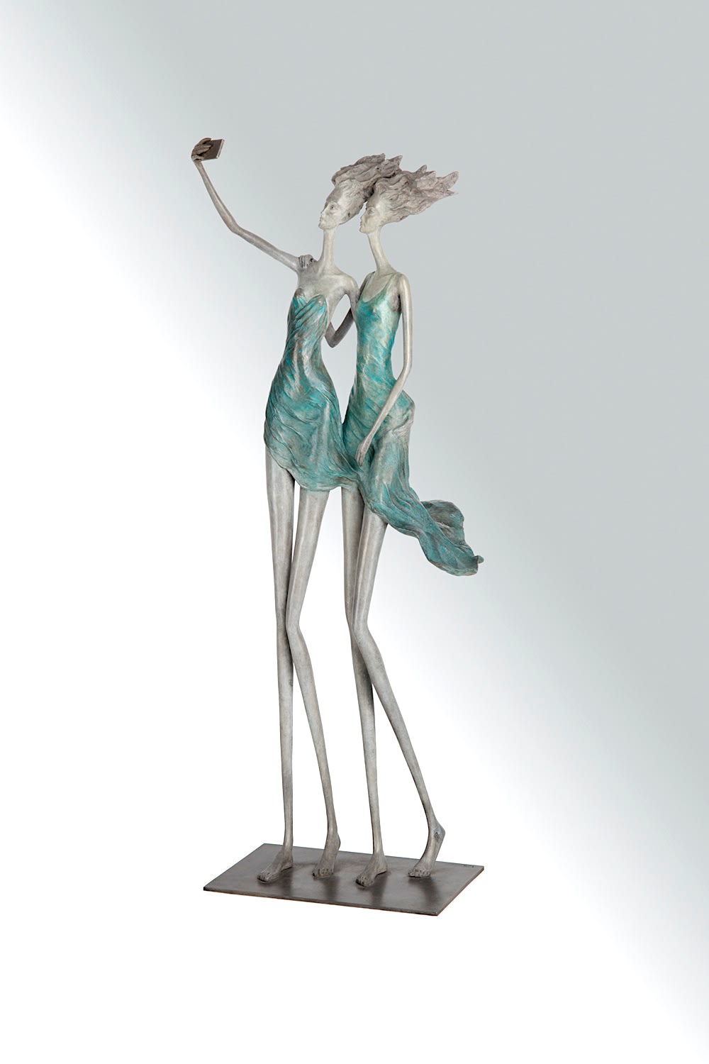 Best Friends Ever two girls sculpture of Hedwige Leroux contemporary bronze sculpture dancer woman sculpture two girls sisters in a green and blue dress taking a selfy with telephone together at Art Yi gallery in Brussels