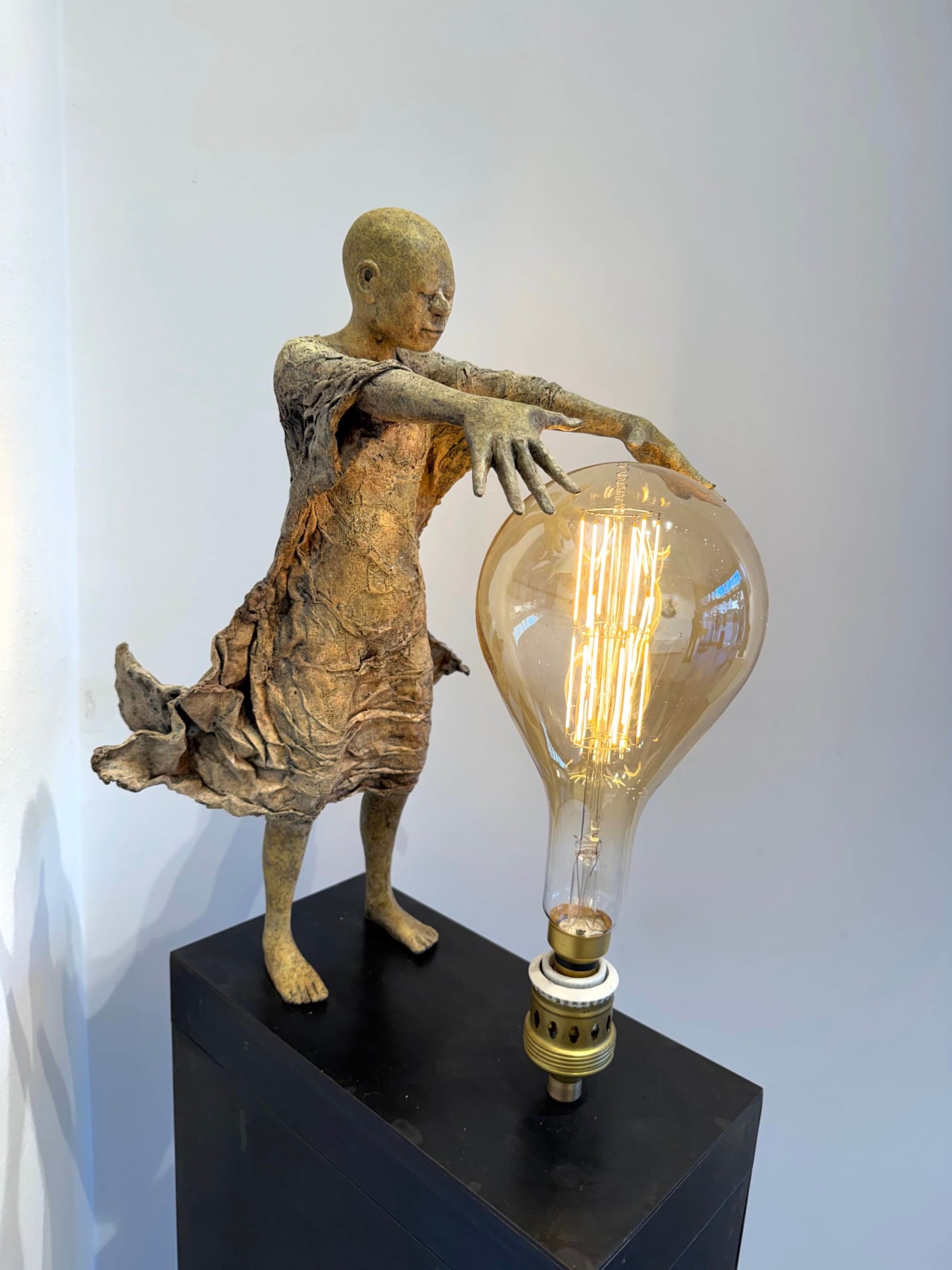 IIXV Visionary XL with light boy sculpture bronze sculpture of Lieven d'Haese garden sculpture boy opening arms to light up a light bulb in his hands with imagination magic dream contemporary art sculpture light interior design at Art Yi gallery in Brussels