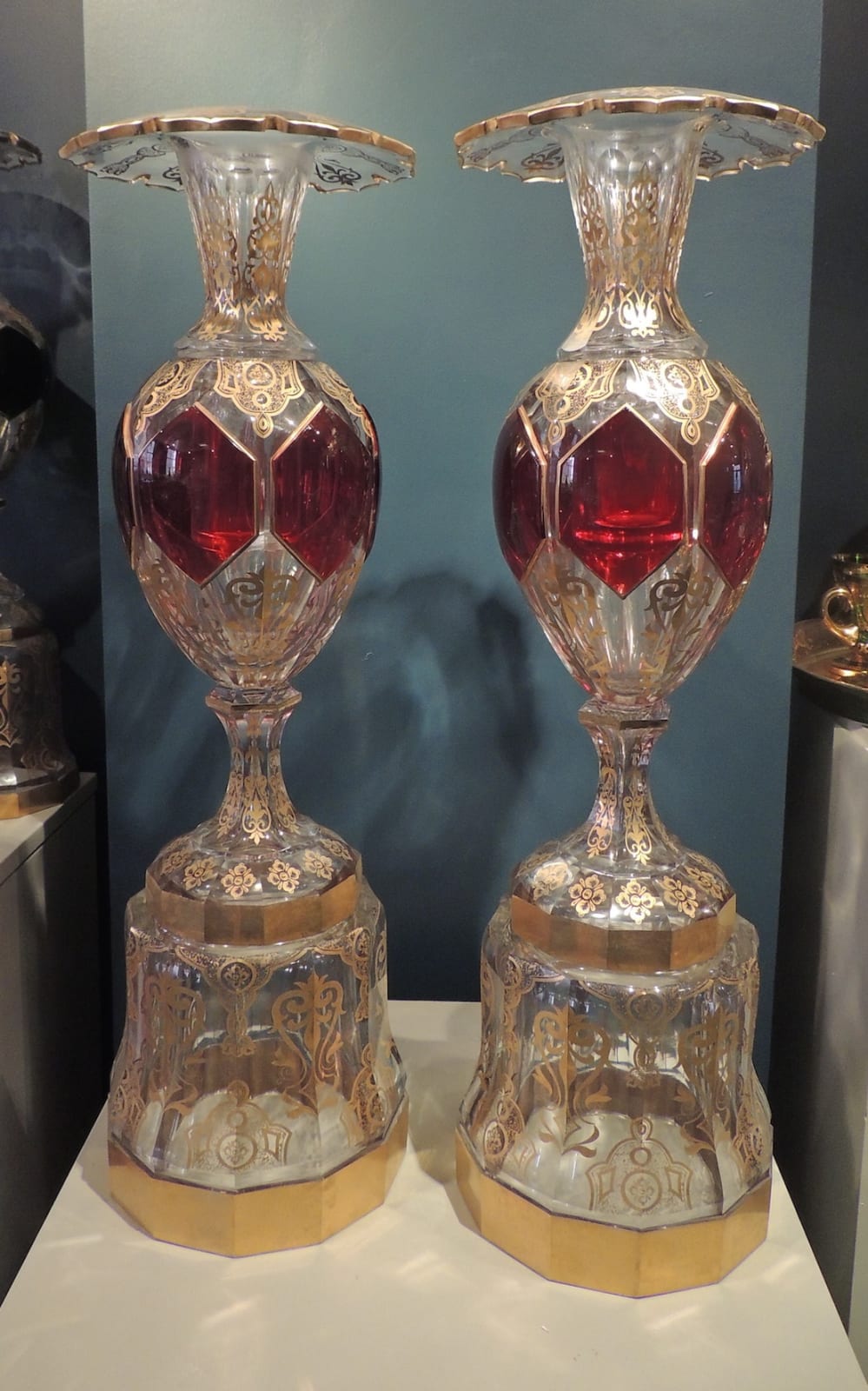 Pair of glass vases in gold and red on pedestals