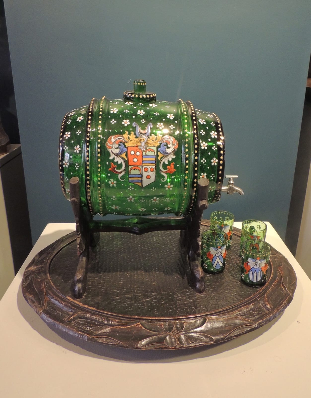 Green glass barrel on stand accompanied by four minute glasses, similarly decorated