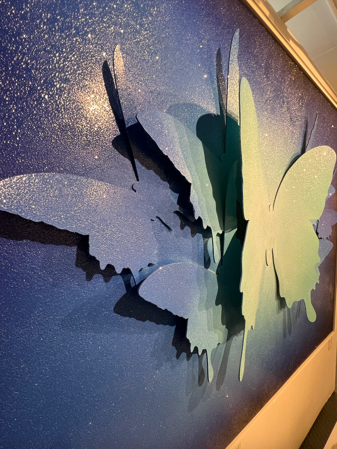 Detail photo of “357”, mixed media artwork by Punk Me Tender artist from France, based in LA. Available at Carousel Fine Art Miami. The artist’s technique involves acrylic on wood panel, aluminum butterflies, and diamond dust. The butterfly, a signature element in his work, is used to create a transformative experience for viewers. Colors of this work hues of: Blue, Diamond Dust