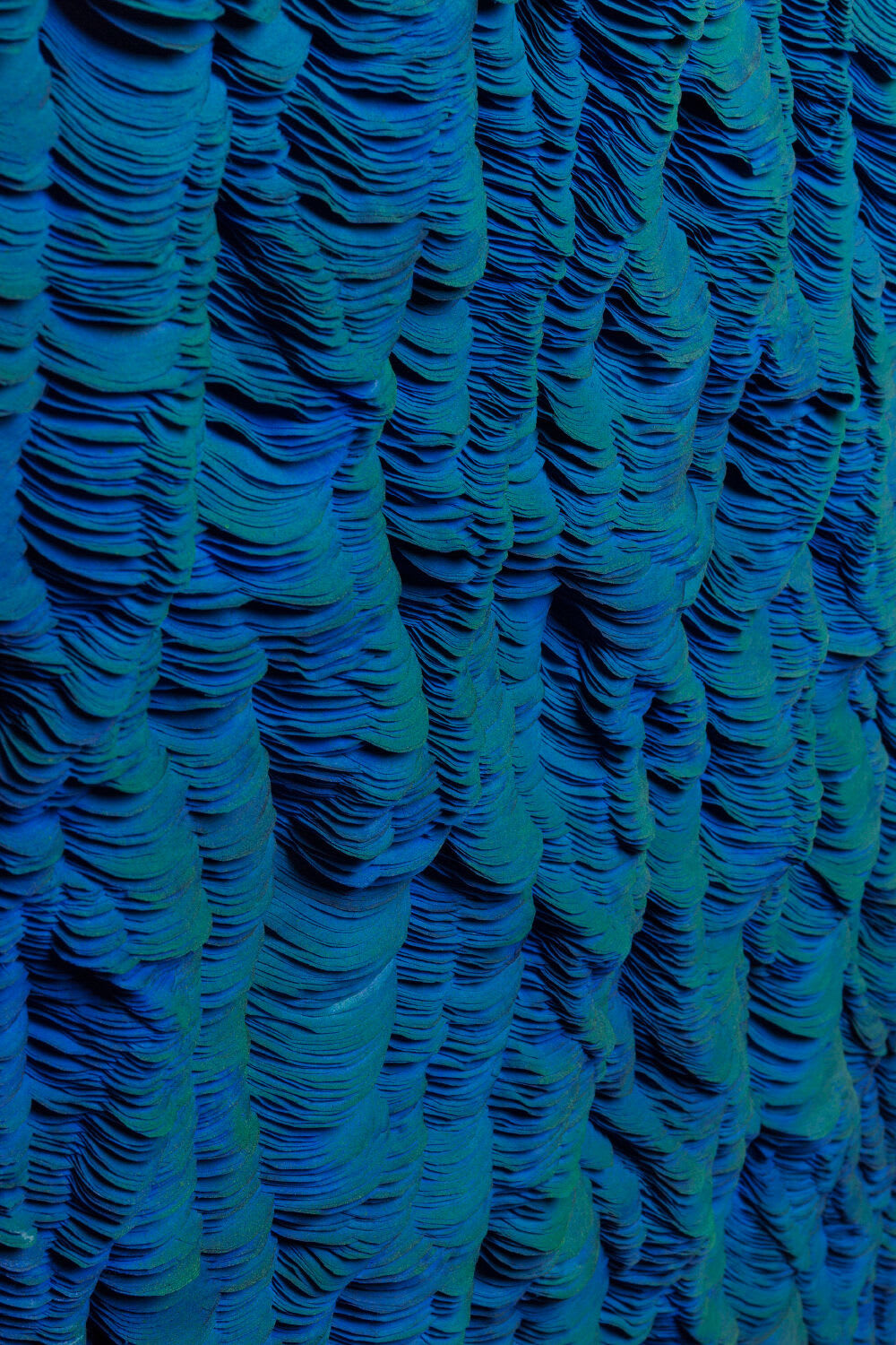 Detail photo of “Ocean #14”, sculptural paper work by Javier Leon Perez, artist from Spain. Available at Carousel Fine Art Miami. The artist’s technique uses Japanese paper with ink and pigment paint in an acrylic box to explore forms, light, and folds. This approach offers a personal expression that invites viewers to listen to their own thoughts and immerse themselves in a sensory journey. Colors of this work : Blue, Green