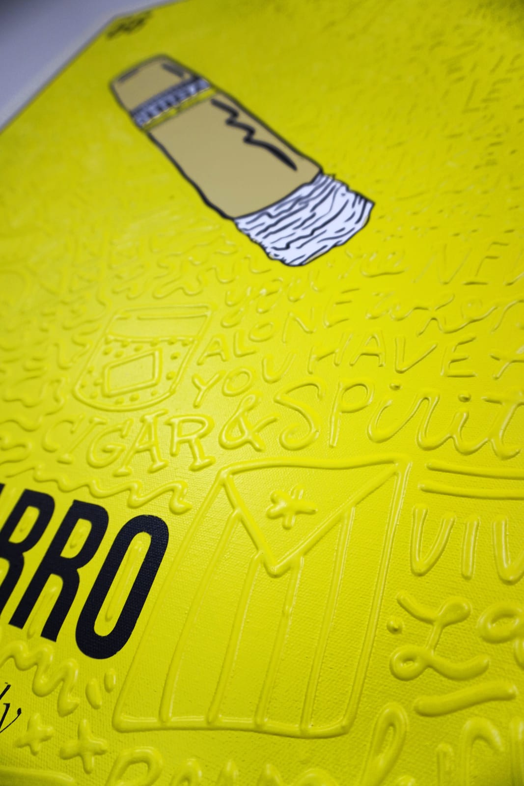 Detail photo of “El Cigarro”, painting by Cayla Birk artist from South Florida. Available at Carousel Fine Art Chicago. The artist’s technique blends traditional acrylic paints with unique materials, creating a distinct mixed media style. Birk's work is marked by intricate designs and recognizable gestures, combining contemporary culture, history, music, and literature. Her art challenges conventional thinking, offering new and unexpected experiences. Colors of this work : Yellow, Beige, White, Black