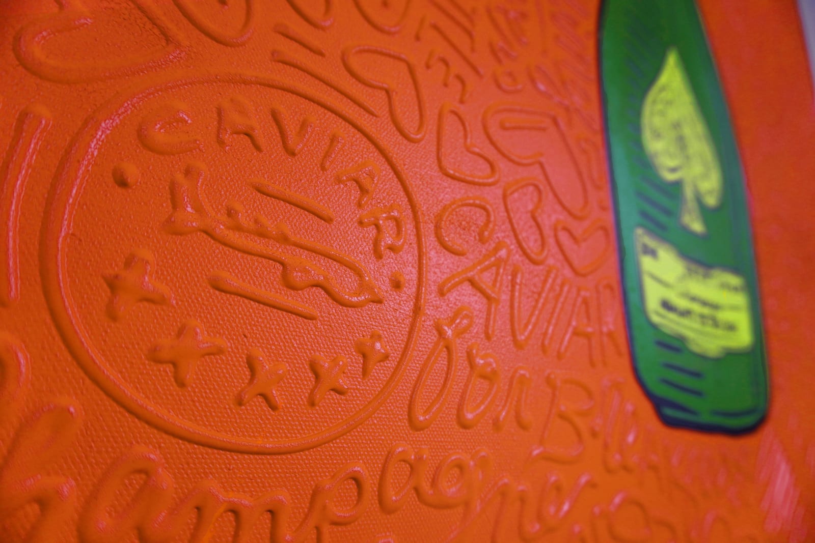 Detail photo of “La Botella”, painting by Cayla Birk artist from South Florida. Available at Carousel Fine Art Atlanta. The artist’s technique blends traditional acrylic paints with unique materials, creating a distinct mixed media style. Birk's work is marked by intricate designs and recognizable gestures, combining contemporary culture, history, music, and literature. Her art challenges conventional thinking, offering new and unexpected experiences. Colors of this work : Orange, Green, Yellow, Beige, Black