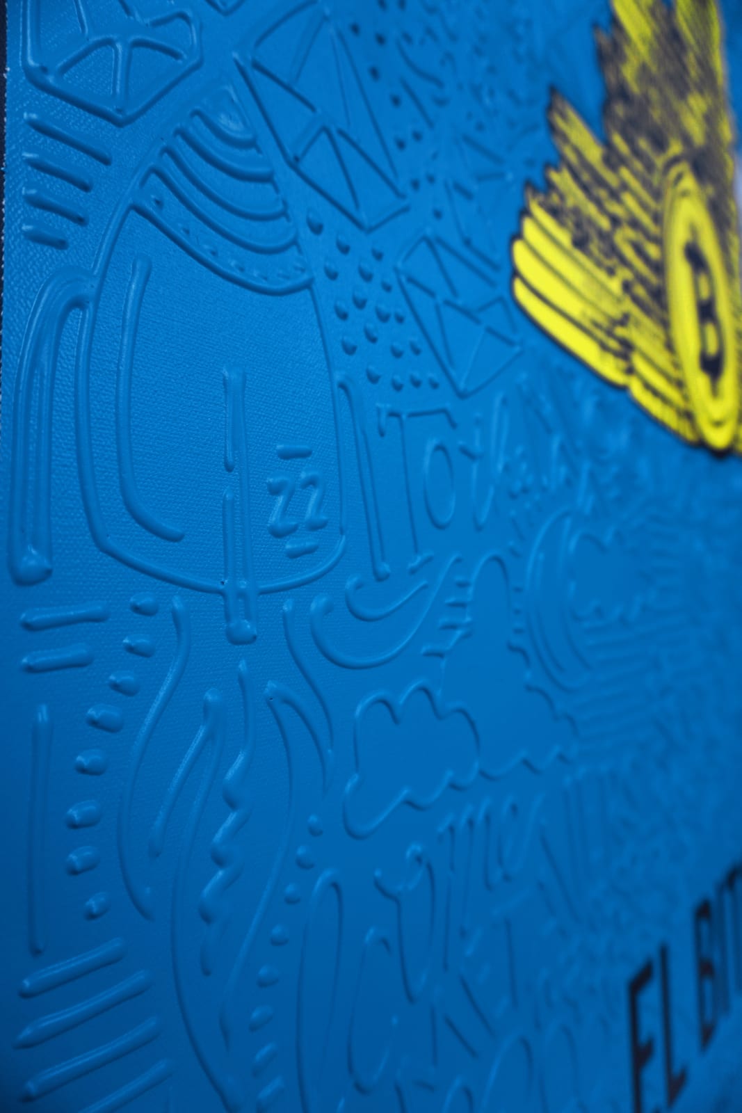 Detail photo of “El Bitcoin”, painting by Cayla Birk artist from South Florida. Available at Carousel Fine Art Atlanta. The artist’s technique blends traditional acrylic paints with unique materials, creating a distinct mixed media style. Birk's work is marked by intricate designs and recognizable gestures, combining contemporary culture, history, music, and literature. Her art challenges conventional thinking, offering new and unexpected experiences. Colors of this work : Blue, Yellow, Grey, White, Black