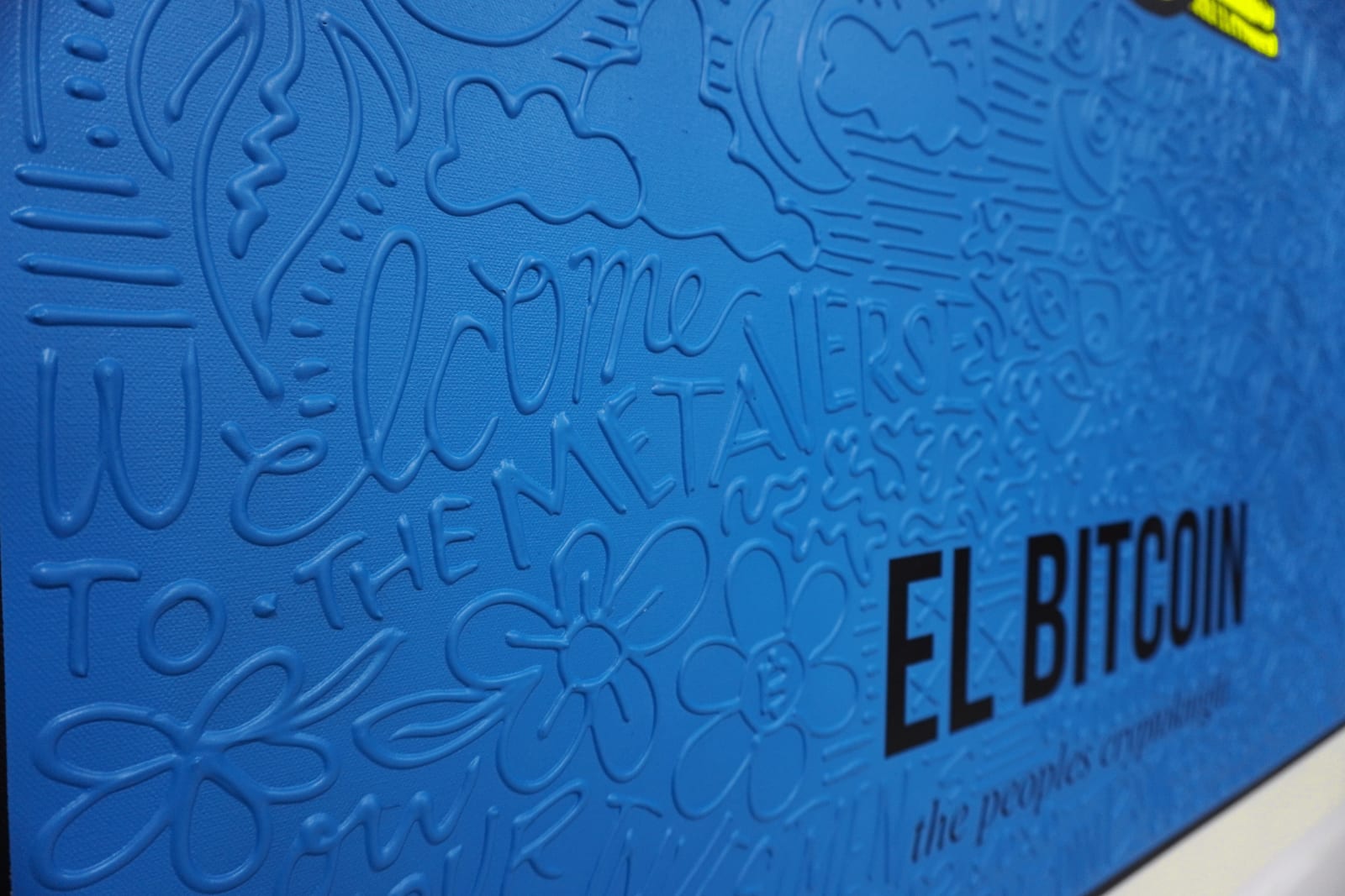 Detail photo of “El Bitcoin”, painting by Cayla Birk artist from South Florida. Available at Carousel Fine Art Atlanta. The artist’s technique blends traditional acrylic paints with unique materials, creating a distinct mixed media style. Birk's work is marked by intricate designs and recognizable gestures, combining contemporary culture, history, music, and literature. Her art challenges conventional thinking, offering new and unexpected experiences. Colors of this work : Blue, Yellow, Grey, White, Black