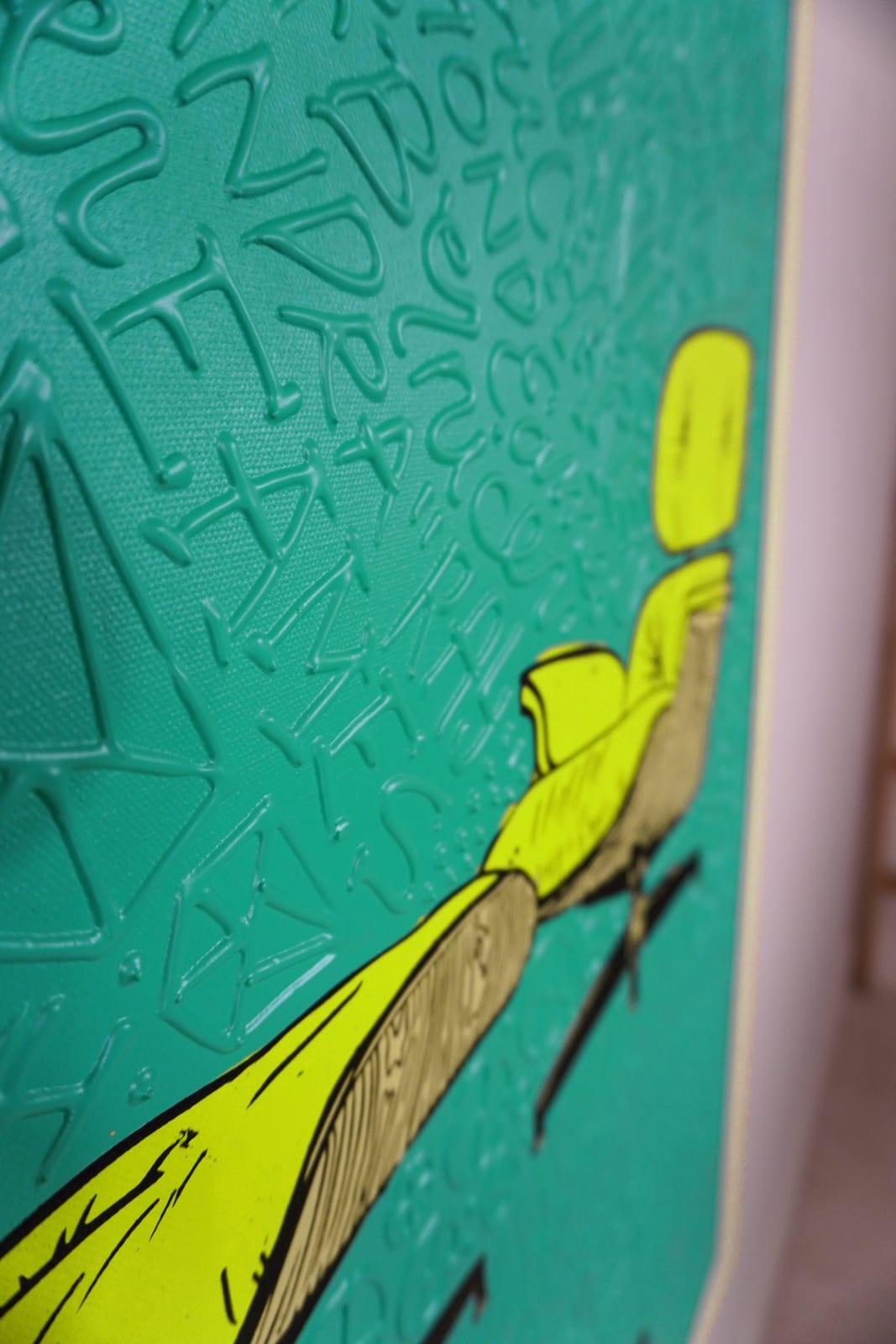 Detail photo of “El Asiento”, painting by Cayla Birk artist from South Florida. Available at Carousel Fine Art Chicago. The artist’s technique blends traditional acrylic paints with unique materials, creating a distinct mixed media style. Birk's work is marked by intricate designs and recognizable gestures, combining contemporary culture, history, music, and literature. Her art challenges conventional thinking, offering new and unexpected experiences. Colors of this work : Teal, Yellow, Beige, Black