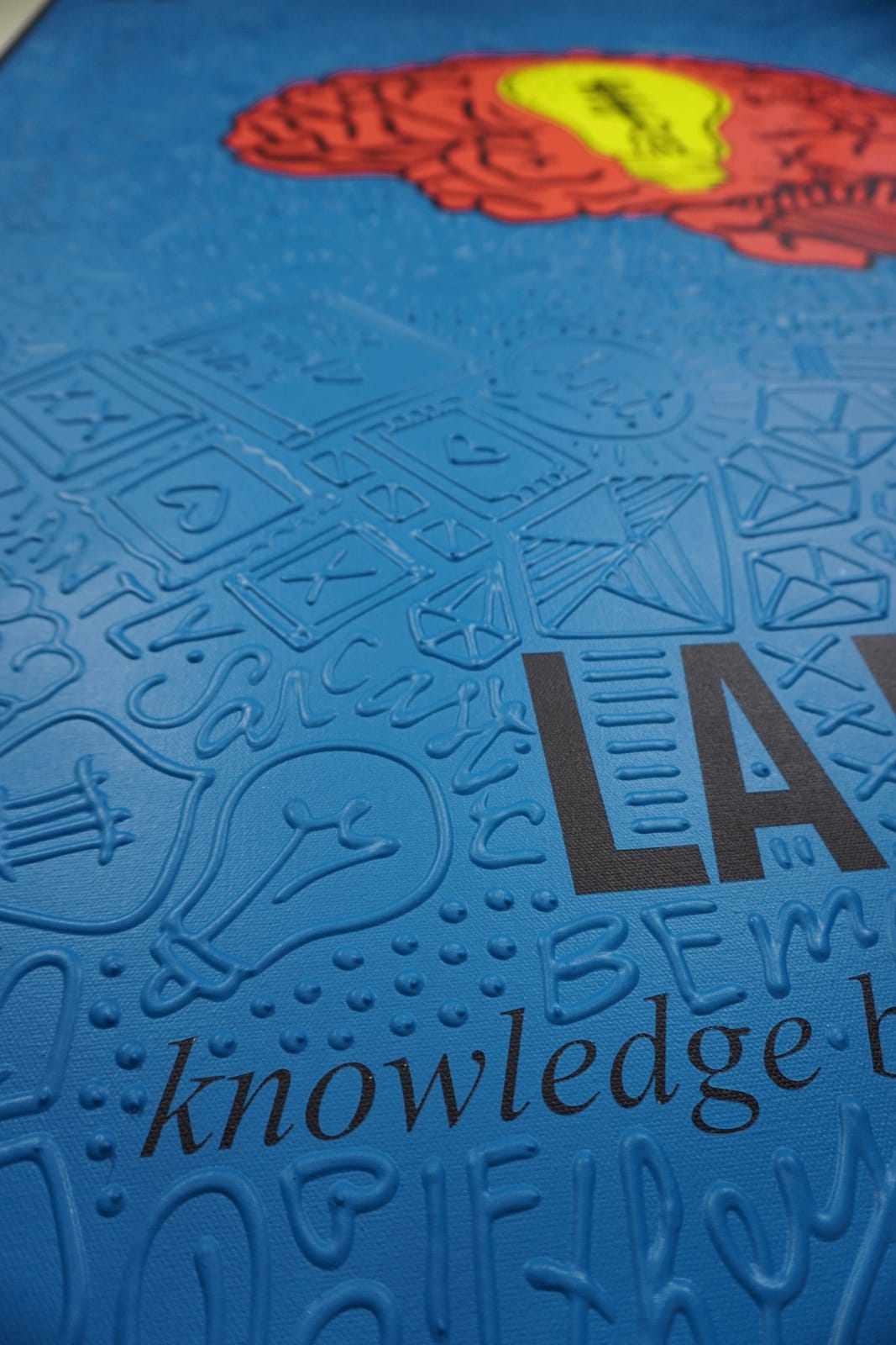 Detail photo of “La Mente”, painting by Cayla Birk artist from South Florida. Available at Carousel Fine Art Chicago. The artist’s technique blends traditional acrylic paints with unique materials, creating a distinct mixed media style. Birk's work is marked by intricate designs and recognizable gestures, combining contemporary culture, history, music, and literature. Her art challenges conventional thinking, offering new and unexpected experiences. Colors of this work : Red, Blue, Yellow, Beige, Black