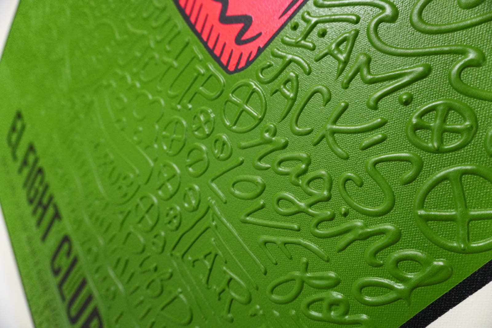 Detail photo of “El Fight Club”, painting by Cayla Birk artist from South Florida. Available at Carousel Fine Art Chicago. The artist’s technique blends traditional acrylic paints with unique materials, creating a distinct mixed media style. Birk's work is marked by intricate designs and recognizable gestures, combining contemporary culture, history, music, and literature. Her art challenges conventional thinking, offering new and unexpected experiences. Colors of this work : Green, Red, Beige, White, Black