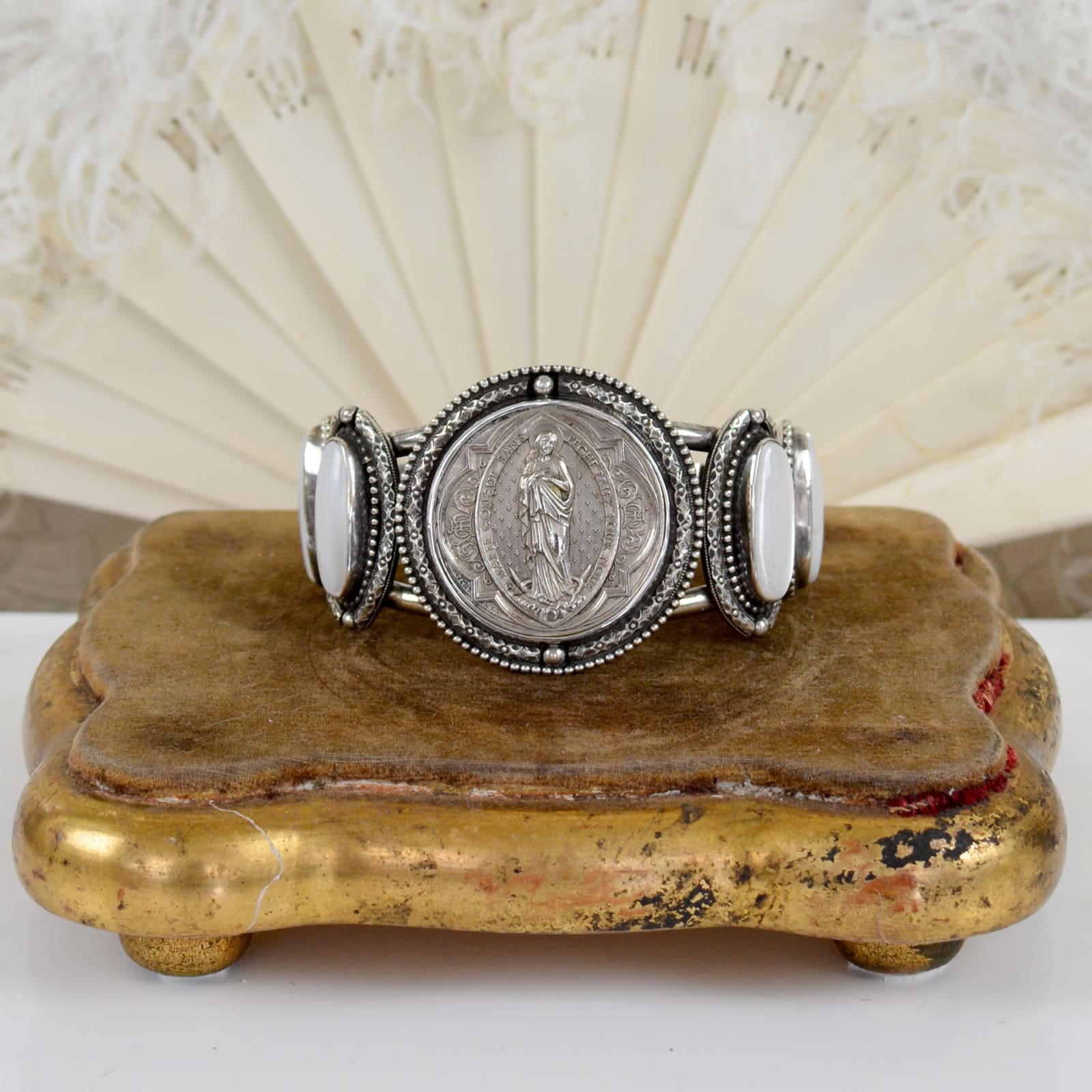 Jill Garber, AN ICONIC WISDOM CUFF CRAFTED WITH A VERY FINE NINETEENTH CENTURY SACRED HEART MEDALLION SIGNED BY MASTER ENGRAVER LUDOVIC PENIN AT CENTER, WITH MOTHER OF PEARL CABOCHONS. BEAUTIFUL MOUNTINGS COMPRISED OF ENGRAVED AND BEADED FRAMES PROVIDES CLASSICAL DETAILS ON THIS THREE ROW CUFF.